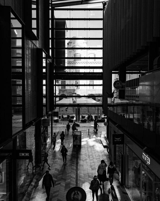 People crossing a modern arcade under a glazed roof