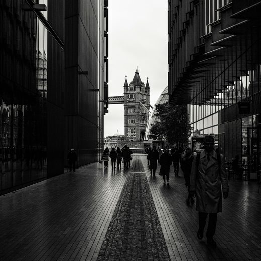 Figures crossing a street between tall buildings